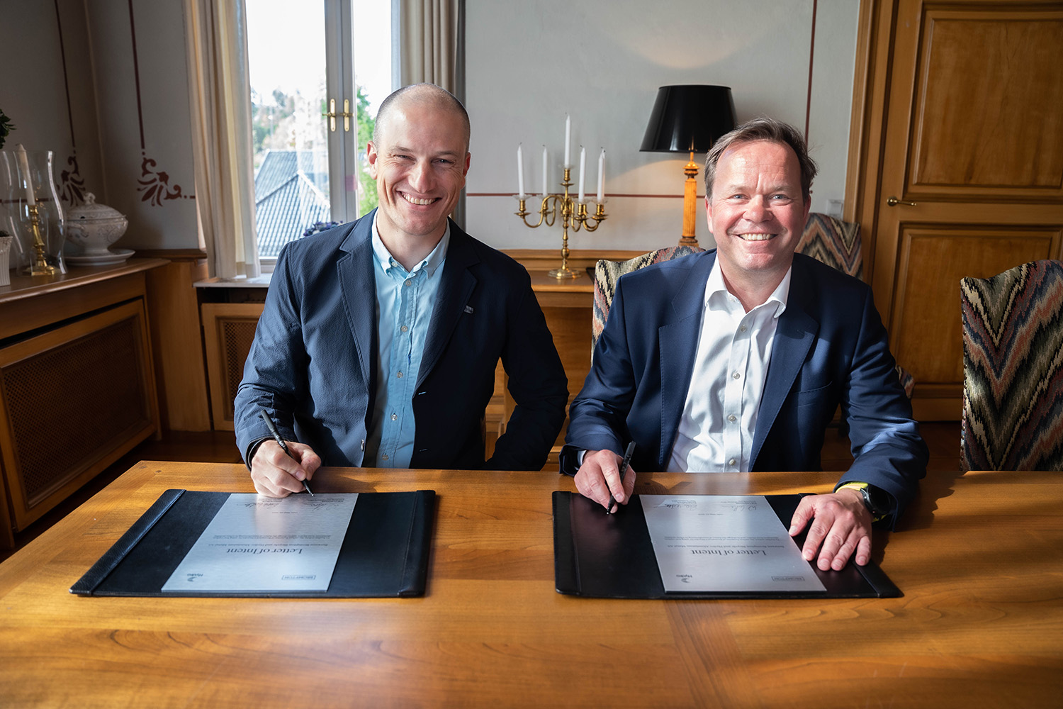 a couple of men sitting at a table with a book and a pen