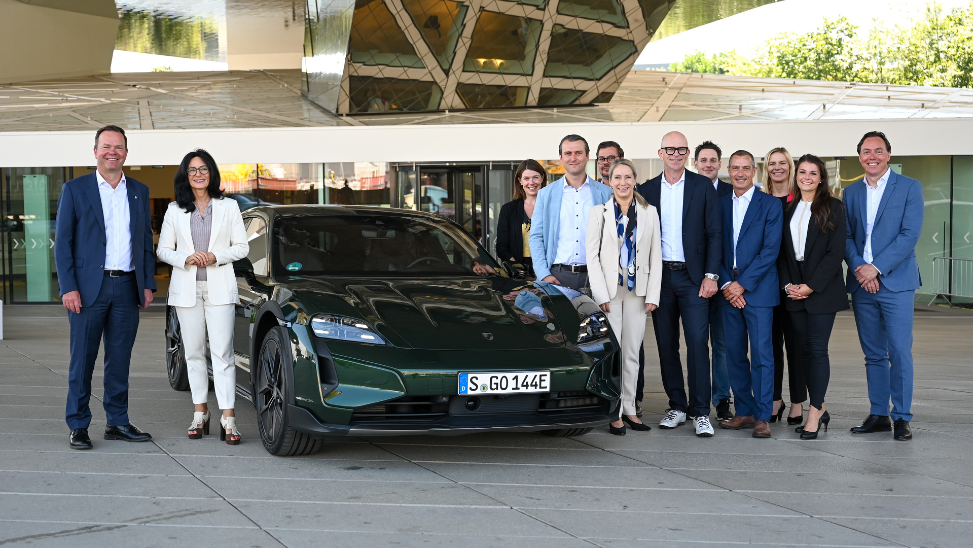 a group of people posing for a photo next to a car