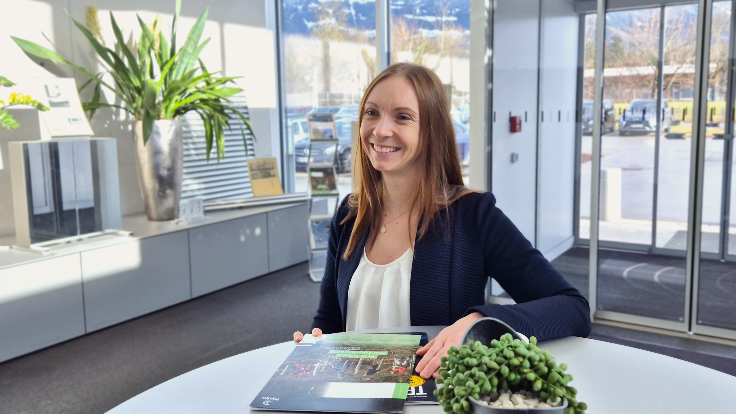 a woman sitting at a table with a plant and a book